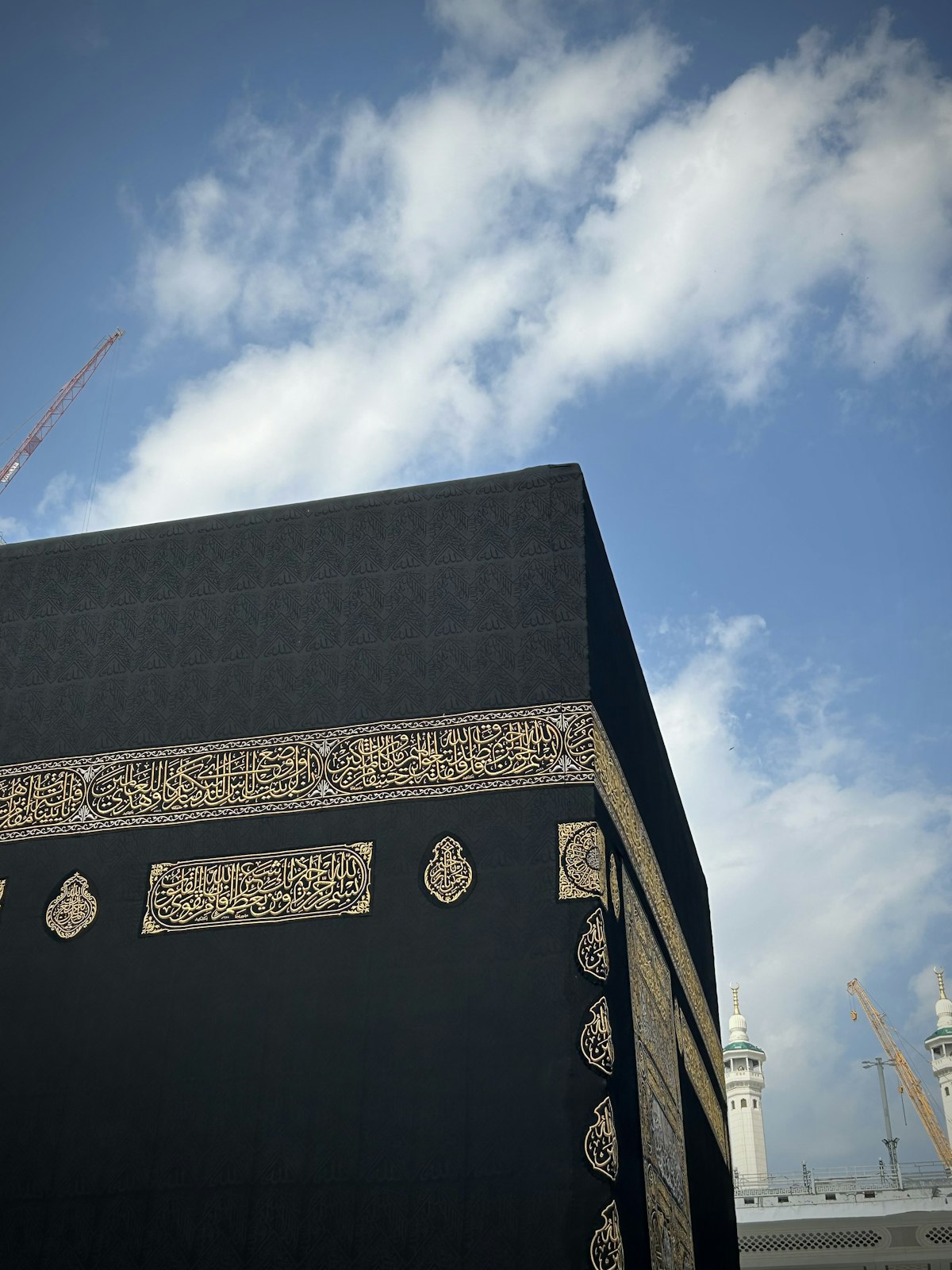La Kaaba drapée de sa kiswa noire brodée d’or, se détachant sur un ciel bleu profond.